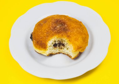 Tabağında çikolata olan ısırılmış çörek. Lezzetli tatlılar cezbedici ve sarı arka planda tatlılar. Minimalizm, orijinal ve yaratıcı bir imaj. Güzel yemek duvar kâğıdı.