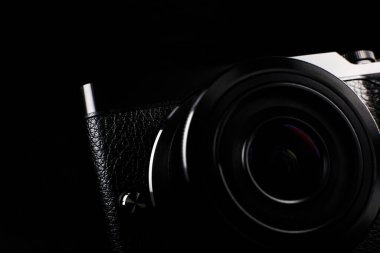 Siyah arka planda lens olan siyah modern kamera. Kapat..