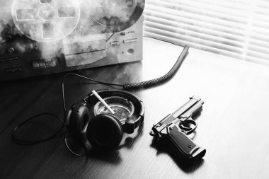 Dinleme için teyp kaydı. KGB casusluk konuşmaları. Siyah silah yakında. Sigaralı kül tablası.