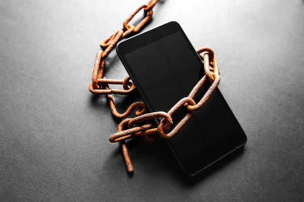 Akıllı telefonun etrafındaki paslı zincirler. Modern teknolojilere bağımlı..