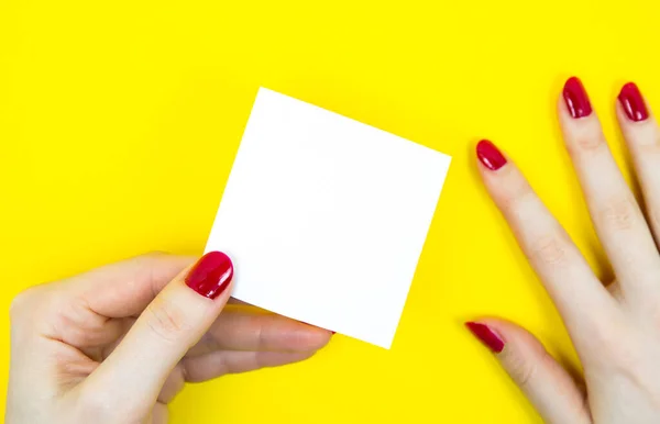 女性の手でリストのステッカーを行うには空白の白 黄色の背景にメモ用紙を閉じます コピースペース ミニマリズム オリジナルで創造的な写真 — ストック写真