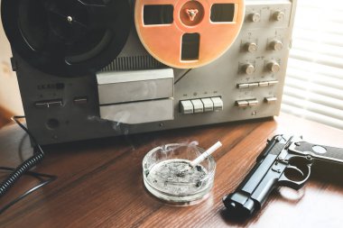 Dinleme için teyp kaydı. KGB casusluk konuşmaları. Siyah silah yakında. Sigaralı kül tablası.