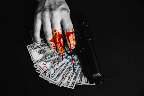 Man with hand in blood is holding a gun. Ill-gotten money on the table. Dollars stolen. Killer criminal concept.