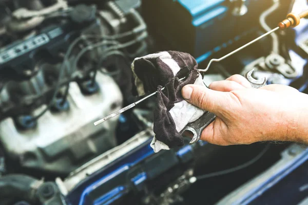 Man holding spark plug in old car engine. Oil level in the tank. Inner details of machine. Repairing of vehicle.