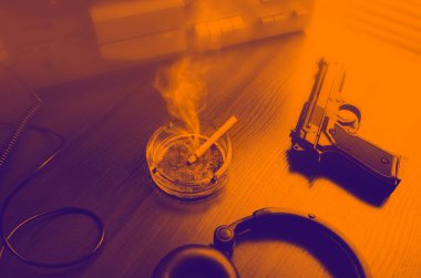 Dinleme için teyp kaydı. KGB casusluk konuşmaları. Siyah silah yakında. Geceleri turuncu renkler. Sigaralı kül tablası.