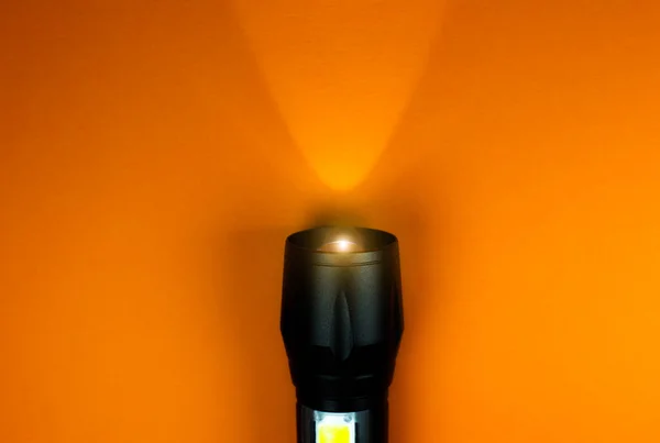 Linterna Negra Rayo Luz Sobre Fondo Naranja Primer Plano Foto — Foto de Stock