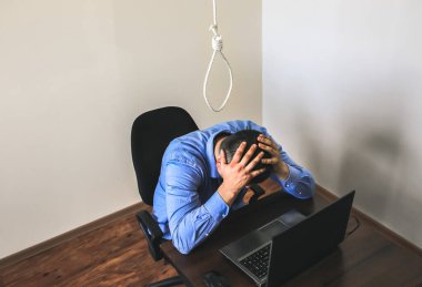 İlmek ofis çalışanının üstünde. İntihar konsepti. İş stresi yüzünden asılmış. Bitkinlik bunalımı. Korkunç bir hayat durumu. Masadaki dizüstü bilgisayarın yanında biri var..
