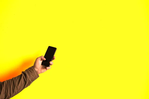 Hombre Sostiene Teléfono Inteligente Manos Aisladas Sobre Fondo Amarillo Adicta — Foto de Stock