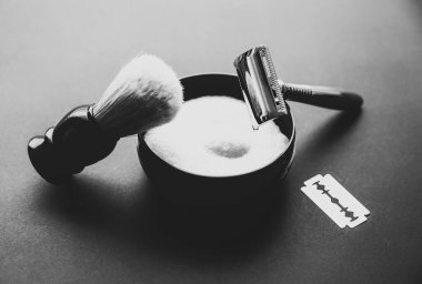 Tıraş fırçası, jilet ve bıçak masanın üstünde. Tarz sahibi adamlar. Hediye fikri. Berber dükkanları. Siyah ve beyaz.