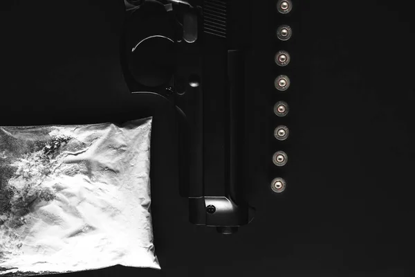 Gun with bullets lying on the table. Criminal problems. Drugs and on black background. Illegal selling.