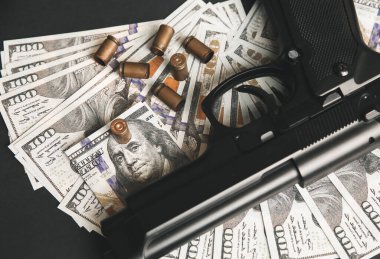 Masada duran mermili silah. Siyah arka planda para. Suç sorunları. Dolar..