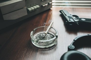 Dinleme için teyp kaydı. KGB casusluk konuşmaları. Siyah silah yakında. Sigaralı kül tablası.