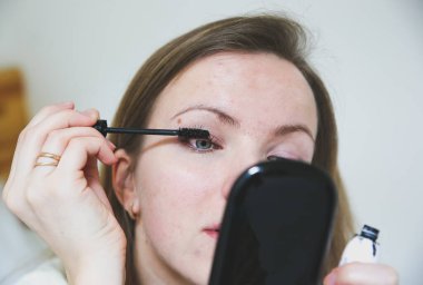 Kız makyaj yapıyor. Kirpiklerde siyah rimel. Güzellik fotoğrafı konsepti.