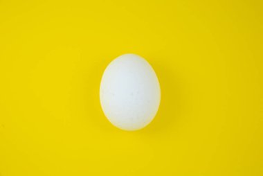 Sarı arka planda beyaz yumurta. Uzayı kopyala Minimalizm, orijinal ve yaratıcı fotoğraf. Güzel duvar kağıdı. Paskalya tatili.