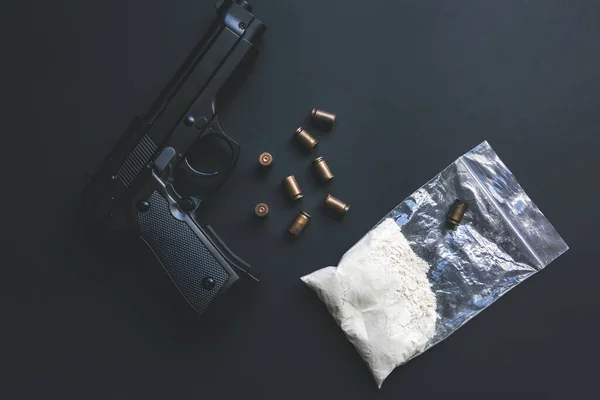 Gun with bullets lying on the table. Criminal problems. Drugs in the packet. Illegal selling.