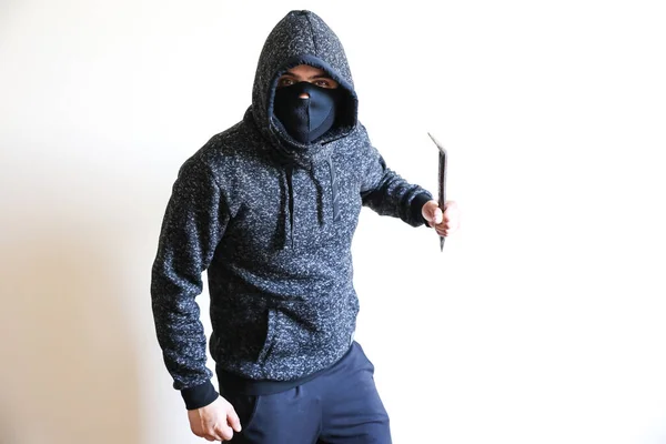 Criminal with crowbar near the doors. Robber in dark hoodie.