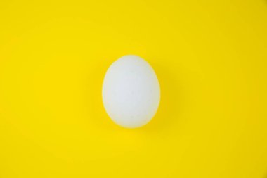 Sarı arka planda beyaz yumurta. Uzayı kopyala Minimalizm, orijinal ve yaratıcı fotoğraf. Güzel duvar kağıdı. Paskalya tatili.