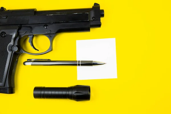 Pistola Negra Papel Recordatorio Bolígrafo Linterna Encuentra Sobre Fondo Amarillo — Foto de Stock