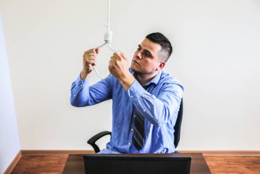 İlmek ofis çalışanının üstünde. İntihar konsepti. İş stresi yüzünden asılmış. Bitkinlik bunalımı. Korkunç bir hayat durumu. Masadaki dizüstü bilgisayarın yanında biri var..