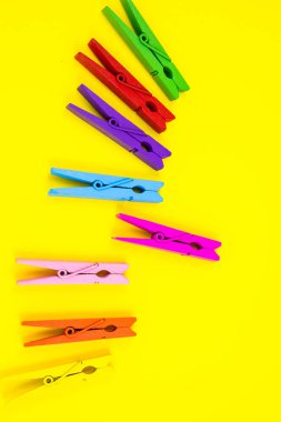 Sarı arka planda renkli ahşap mandallar. Yaklaş, kopyalama alanı. Minimalizm, orijinal ve yaratıcı fotoğraf. Başka biri ol. Bireysellik kavramı.