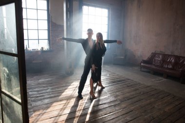 İki profesyonel balo dansçısı çatı katında dans ediyor. Ağır dumanla güzel bir sanat gösterisi. Spor hayatı konsepti. Tutku ve duygusal dans.