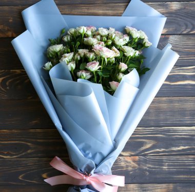 Ahşap arka planda güzel çiçekler. Gül buketi. Taç yapraklarıyla mükemmel bir düzlük. Annemin tatil kartpostalı kutlu olsun. Uluslararası Kadınlar Günü selamı. Reklam veya tanıtım için şık bir fikir.