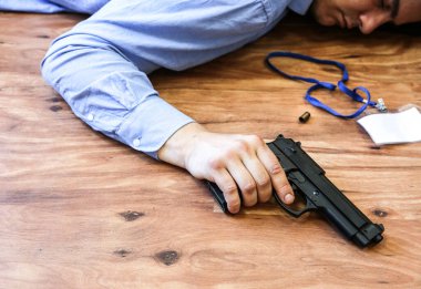 Ofis çalışanı elinde silahla yerde yatıyor. İş stresi yüzünden intihar. Depresyon ya da tükenme. Korkunç bir hayat durumu. Masadaki dizüstü bilgisayarın yanında biri var..