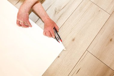 Adam yerdeki duvar kağıtlarını kesiyor. Bakım onarımı dairede tadilat yapıyor. İçerideki restorasyon.