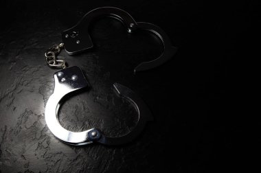 Polis metali siyah arka planda gerçek kelepçeler. Suç ve soygun, hapishane kavramı.