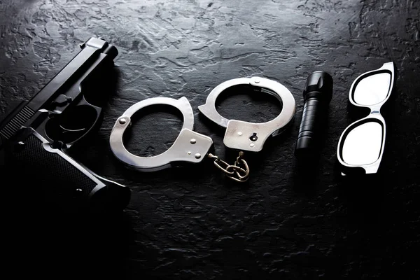 Schwarze Pistole Taschenlampe Brille Und Polizeihandschellen Liegen Auf Dem Schwarzen — Stockfoto