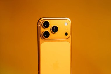 KYIV, UKRAINE - 22 Ocak 2026: Turuncu arka planda Apple iPhone 17 Pro. Kameralı arka panel, kapat.