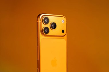 KYIV, UKRAINE - 22 Ocak 2026: Turuncu arka planda Apple iPhone 17 Pro. Kameralı arka panel, kapat.