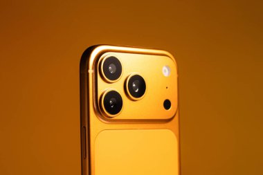 KYIV, UKRAINE - 22 Ocak 2026: Turuncu arka planda Apple iPhone 17 Pro. Kameralı arka panel, kapat.