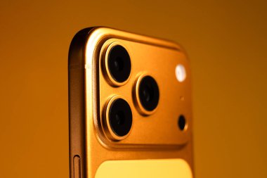 KYIV, UKRAINE - 22 Ocak 2026: Turuncu arka planda Apple iPhone 17 Pro. Kameralı arka panel, kapat.