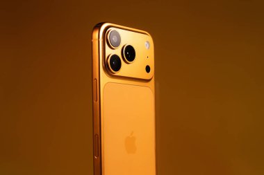 KYIV, UKRAINE - 22 Ocak 2026: Turuncu arka planda Apple iPhone 17 Pro. Kameralı arka panel, kapat.