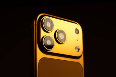 KYIV, UKRAINE - 22 Ocak 2026: Modern akıllı telefon Apple iPhone Pro in Orange color on black background. Kameralı arka panel, kapat.