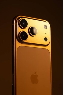 KYIV, UKRAINE - 22 Ocak 2026: Turuncu arka planda Apple iPhone 17 Pro. Kameralı arka panel, kapat. Dikey fotoğraf.