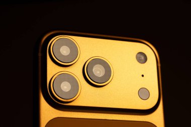 KYIV, UKRAINE - 22 Ocak 2026: Modern akıllı telefon Apple iPhone Pro in Orange color on black background. Kameralı arka panel, kapat.