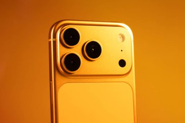 KYIV, UKRAINE - 22 Ocak 2026: Turuncu arka planda Apple iPhone 17 Pro. Kameralı arka panel.