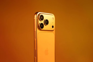 KYIV, UKRAINE - 22 Ocak 2026: Turuncu arka planda Apple iPhone 17 Pro. Kameralı arka panel.