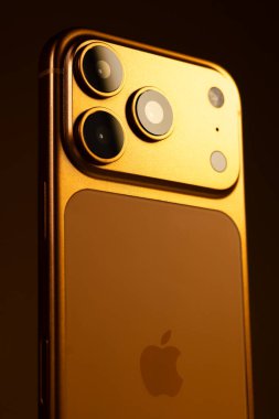 KYIV, UKRAINE - 22 Ocak 2026: Turuncu arka planda Apple iPhone 17 Pro. Kameralı arka panel, kapat. Dikey fotoğraf.