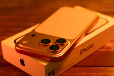 KYIV, UKRAINE - 22 Ocak 2026: Kozmik Turuncu renkli Apple iPhone 17 Pro neon ışıklardaki siyah arkaplanın üzerindeki kutuda yatıyor.