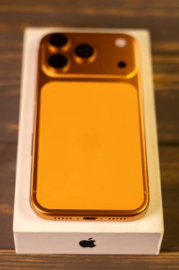 KYIV, UKRAINE - 22 Ocak 2026: Apple iPhone 17 Pro in Cosmic Orange rengi tahta zemin üzerinde yer almaktadır. Dikey fotoğraf.