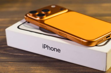 KYIV, UKRAINE - 22 Ocak 2026: Apple iPhone 17 Kozmik Turuncu renkli Pro tahta zemin üzerinde yer almaktadır.