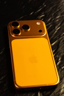 KYIV, UKRAINE - 22 Ocak 2026: Apple iPhone 17 Pro in Cosmic Orange color on black background. Dikey fotoğraf.