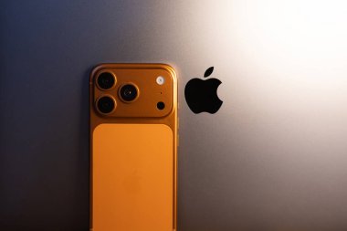 KYIV, UKRAINE - 11 Şubat 2026: Apple iPhone 17 Cosmic Orange renk Pro MacBook laptop ve Apple logosu yakınında kal.