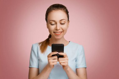 Genç ve güzel bir kız telefonla sohbet ediyor. Elinde aleti olan bir kadın internette geziniyor. Sosyal ağlar ve yeni teknolojiler. Mutlu kız elinde telefonla gülümsüyor.