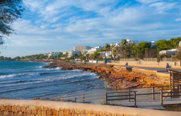 Ibiza St Antoni de Portmany, Ibiza, ahogy arany partvonala kavargó hullámokat a kövek a parton, mint nap Baleár-tenger beállítja novemberben. — Stock Fotó