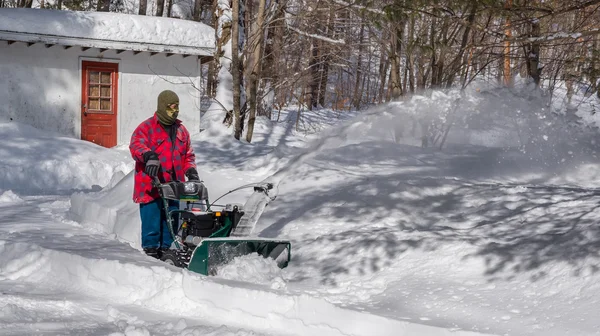 Ένας άνδρας στην εργασία ρούχα, καπέλο και γάντια, λειτουργεί ένα εκχιονιστικό / φυσητήρας μιας χειμερινής μέρας στον Καναδά. — Φωτογραφία Αρχείου