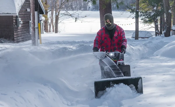 Ein Mann in Arbeitskleidung, Mütze und Handschuhen, der an einem Wintertag in Kanada eine Schneefräse bedient. — Stockfoto